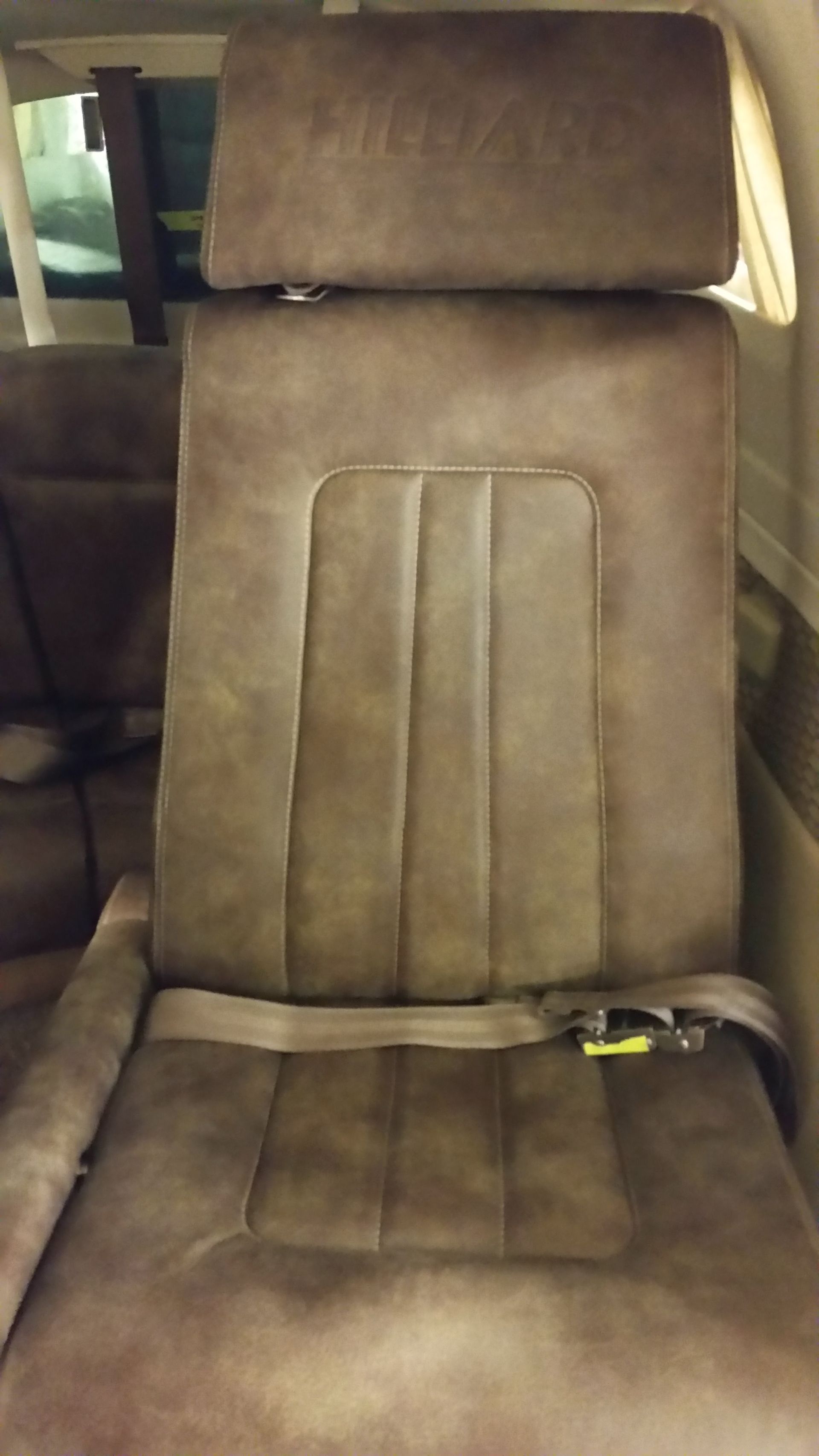 Brown car seat with headrest and seat belt latch visible