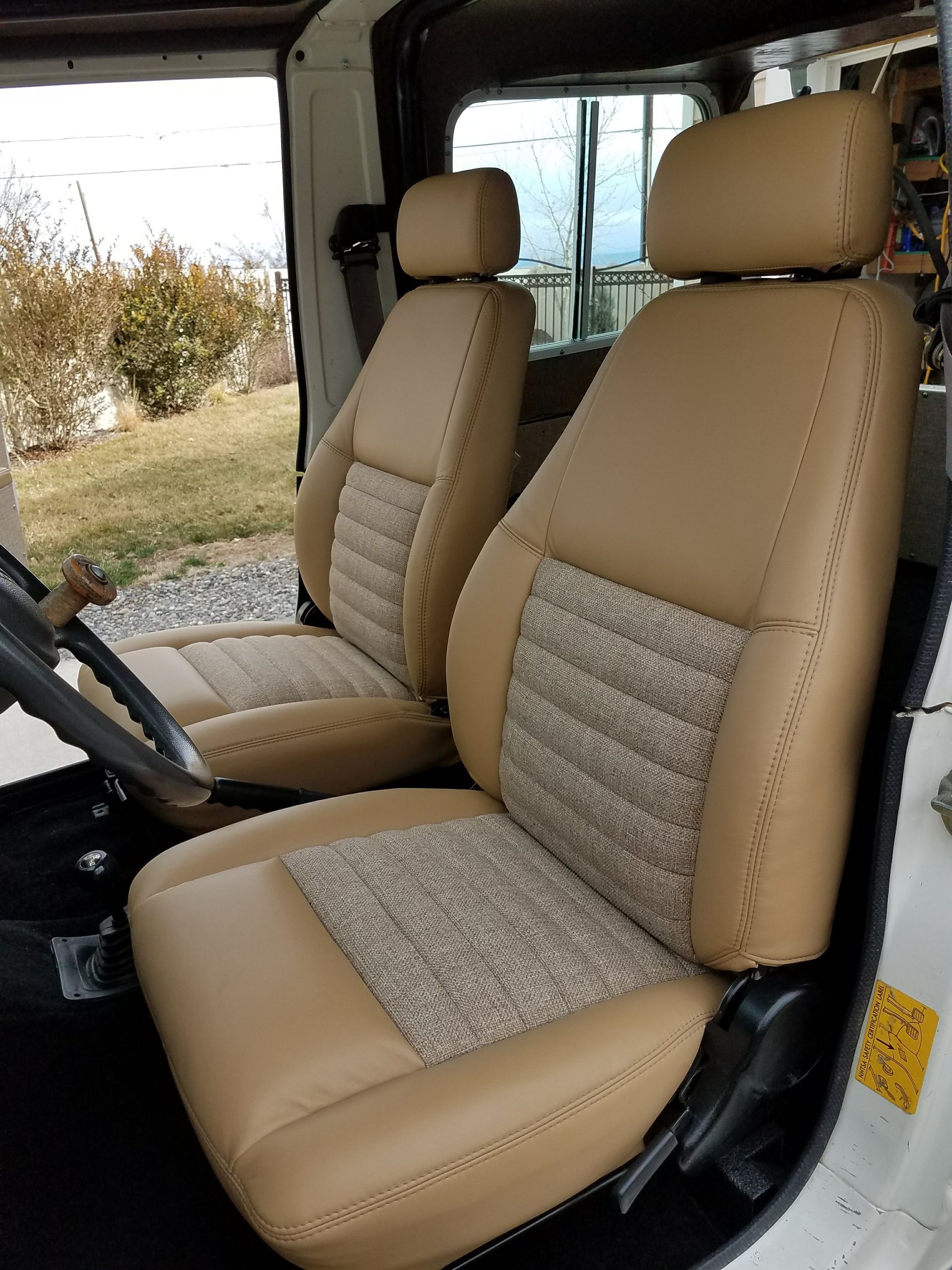 Tan interior of a vehicle with two front seats and a steering wheel visible from the open door