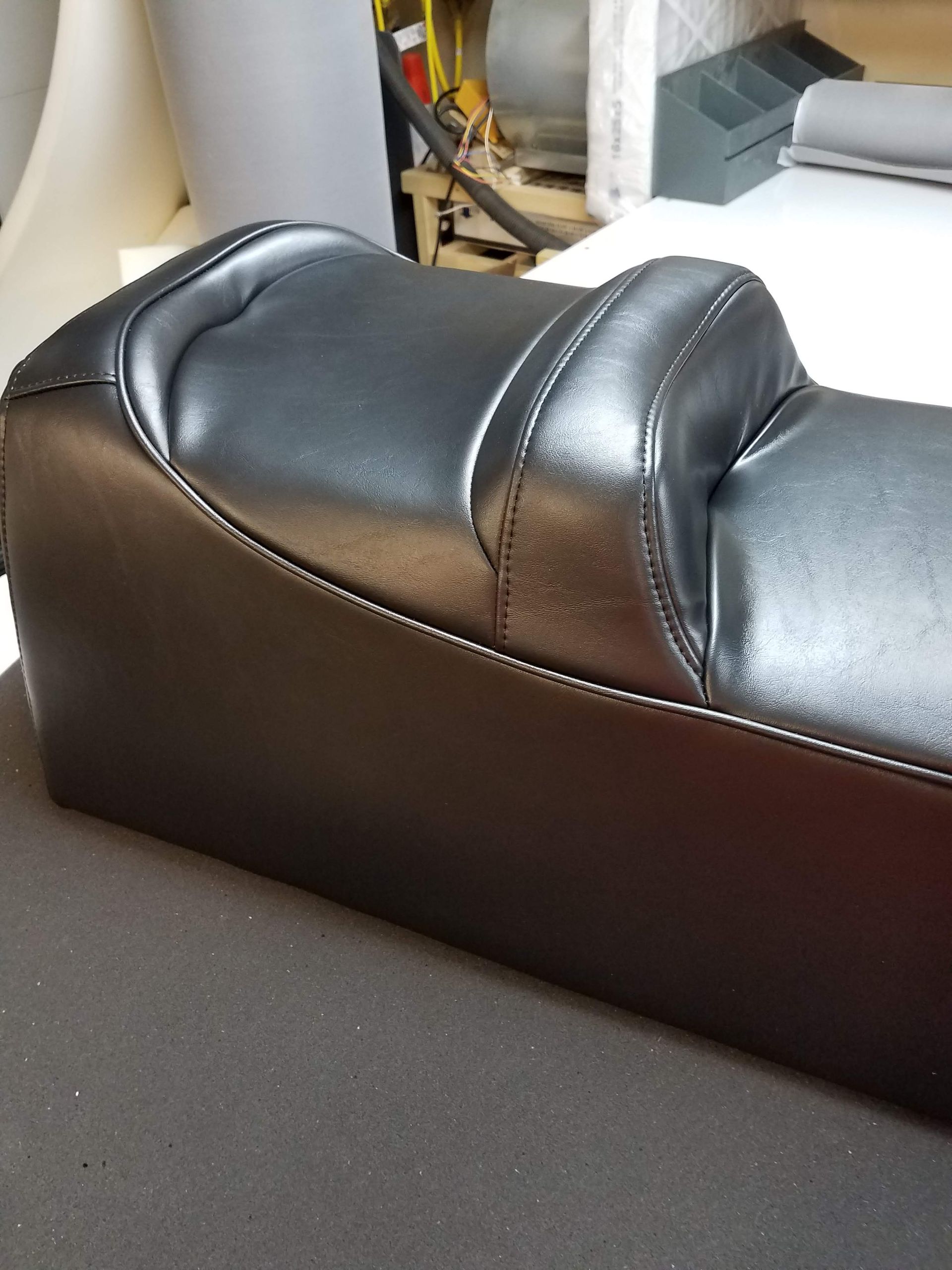 Black leather massage chair seat and backrest in a room, viewed from the side