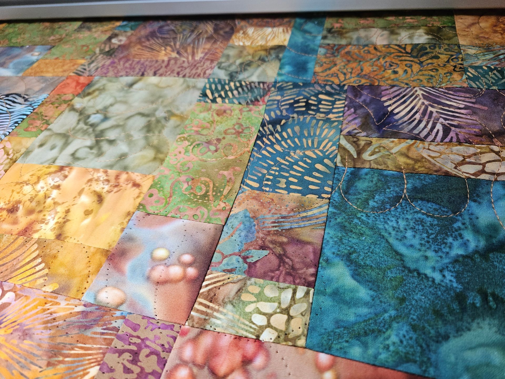 Colorful patchwork of abstract fabric squares in blue, green, purple, and gold patterns
