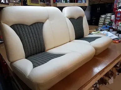 Beige and gray upholstered sofa cushions on a wooden table in a workshop.