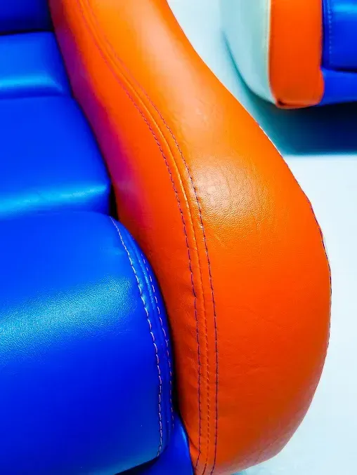 Close-up of blue and orange padded vinyl seating with stitched seam