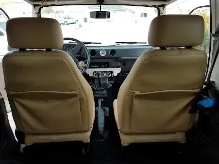Interior of a car from the back seat, showing tan front seats and dashboard
