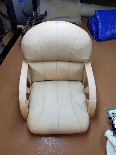Cream leather chair with rounded back and armrests on a brown floor.