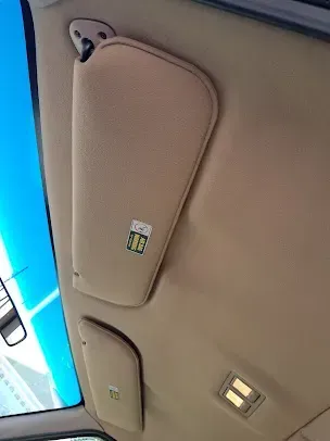 Beige car ceiling with overhead compartments and dome lights near a blue window/door panel