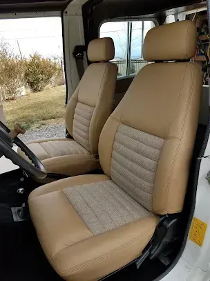Two beige car seats with gray inserts inside a vehicle interior.