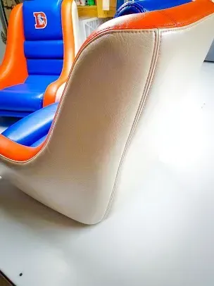 Orange, blue, and white upholstered ride seat with a high back on a white floor