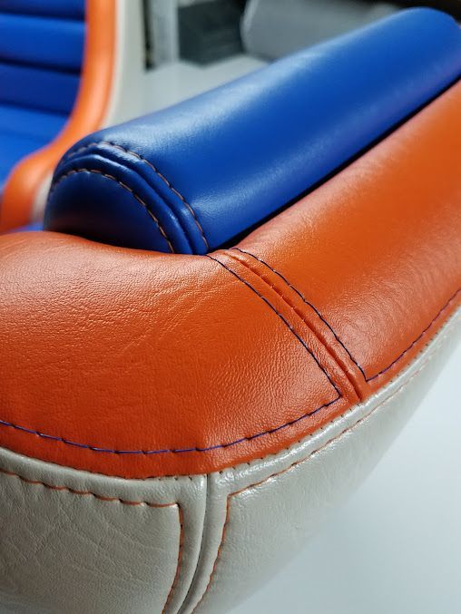 Close-up of a blue and orange upholstered seat corner with stitched seams and white trim