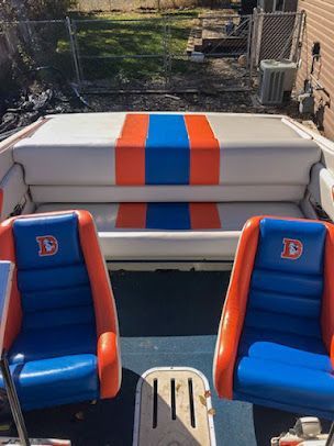 Blue-and-orange boat seats facing a white bench with orange and blue stripes on deck