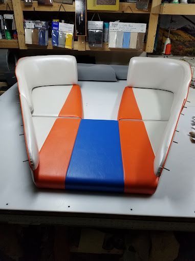 Orange, blue, and white upholstered chair in a workshop on a workbench.