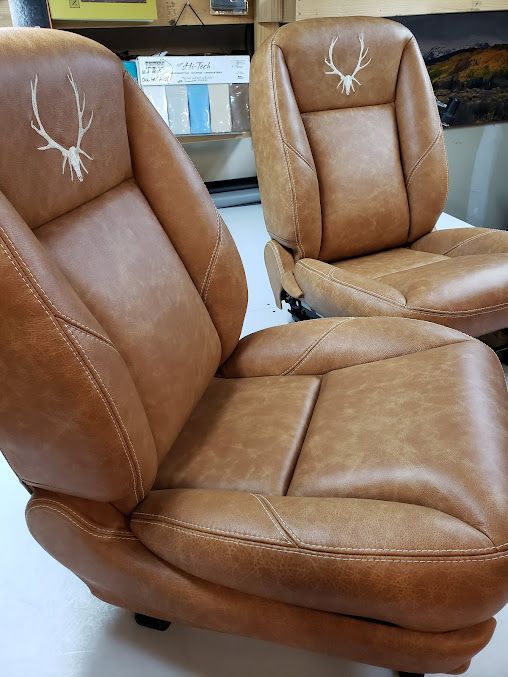 Two brown leather recliner chairs in a showroom, with padded seats and stitched backs