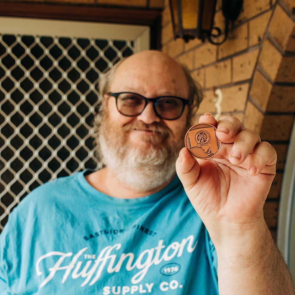 A man wearing a blue shirt holding a coin.