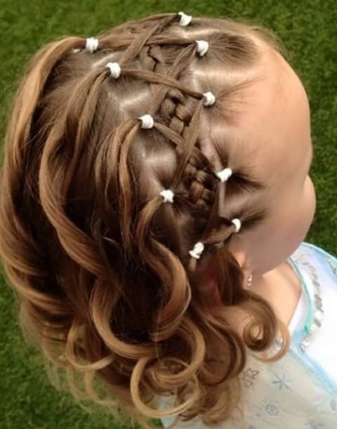 Ein kleines Mädchen trägt eine Flechtfrisur mit Perlen im Haar.