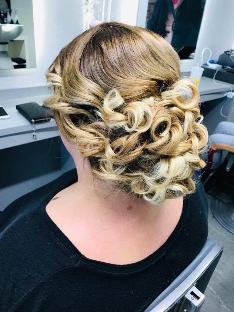 Eine Frau sitzt auf einem Stuhl und hat die Haare zu einem Knoten zusammengebunden.