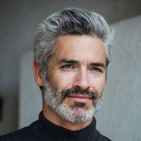 Ein Mann mit grauen Haaren und Bart trägt einen schwarzen Rollkragenpullover.