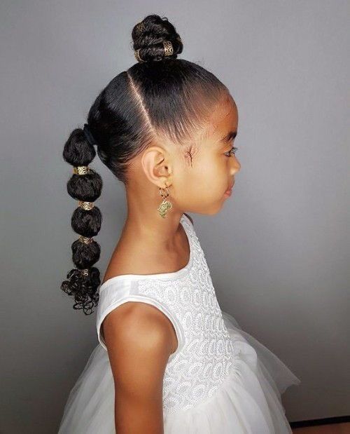 Ein kleines Mädchen in einem weißen Kleid hat die Haare zu einem Knoten zusammengebunden.