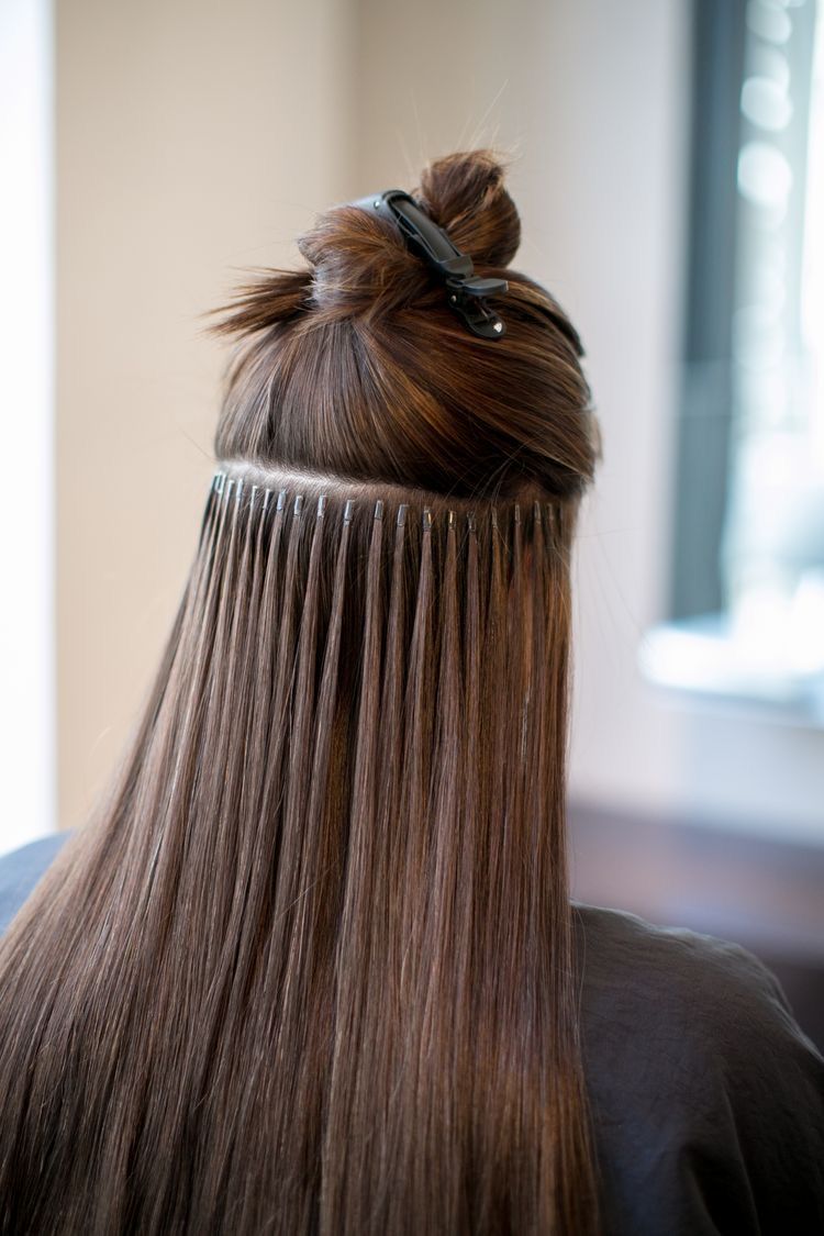 Eine Frau lässt sich in einem Salon die Haare verlängern.