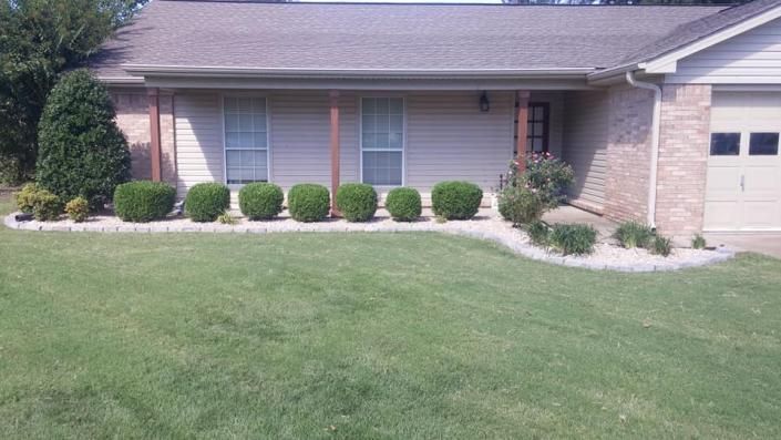 Single-story brick house with a garage, front lawn, and neatly trimmed shrubs.