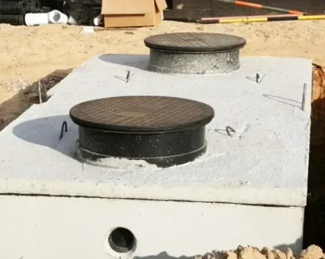 Two black vent caps on a white rooftop base, one larger in front and one smaller behind.