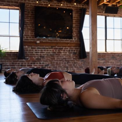 People lying on yoga mats in a brick studio during a relaxation pose
