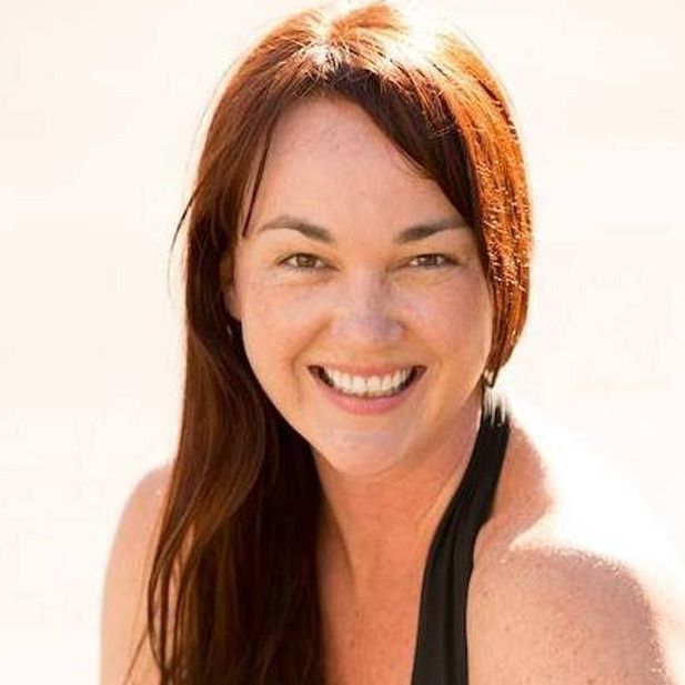 Smiling woman with auburn hair against a bright white background