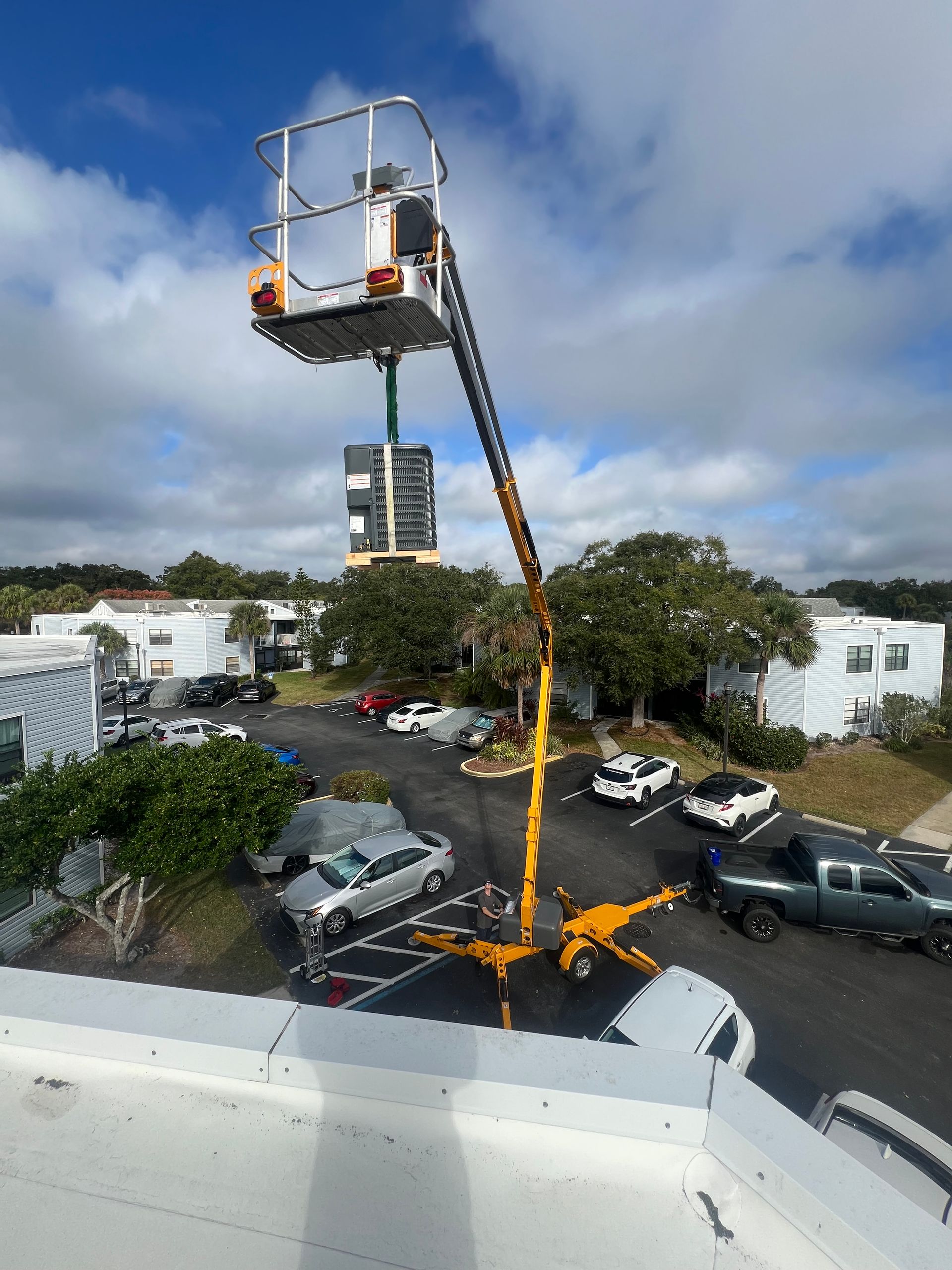 a man is standing in a bucket on a crane in a parking lot