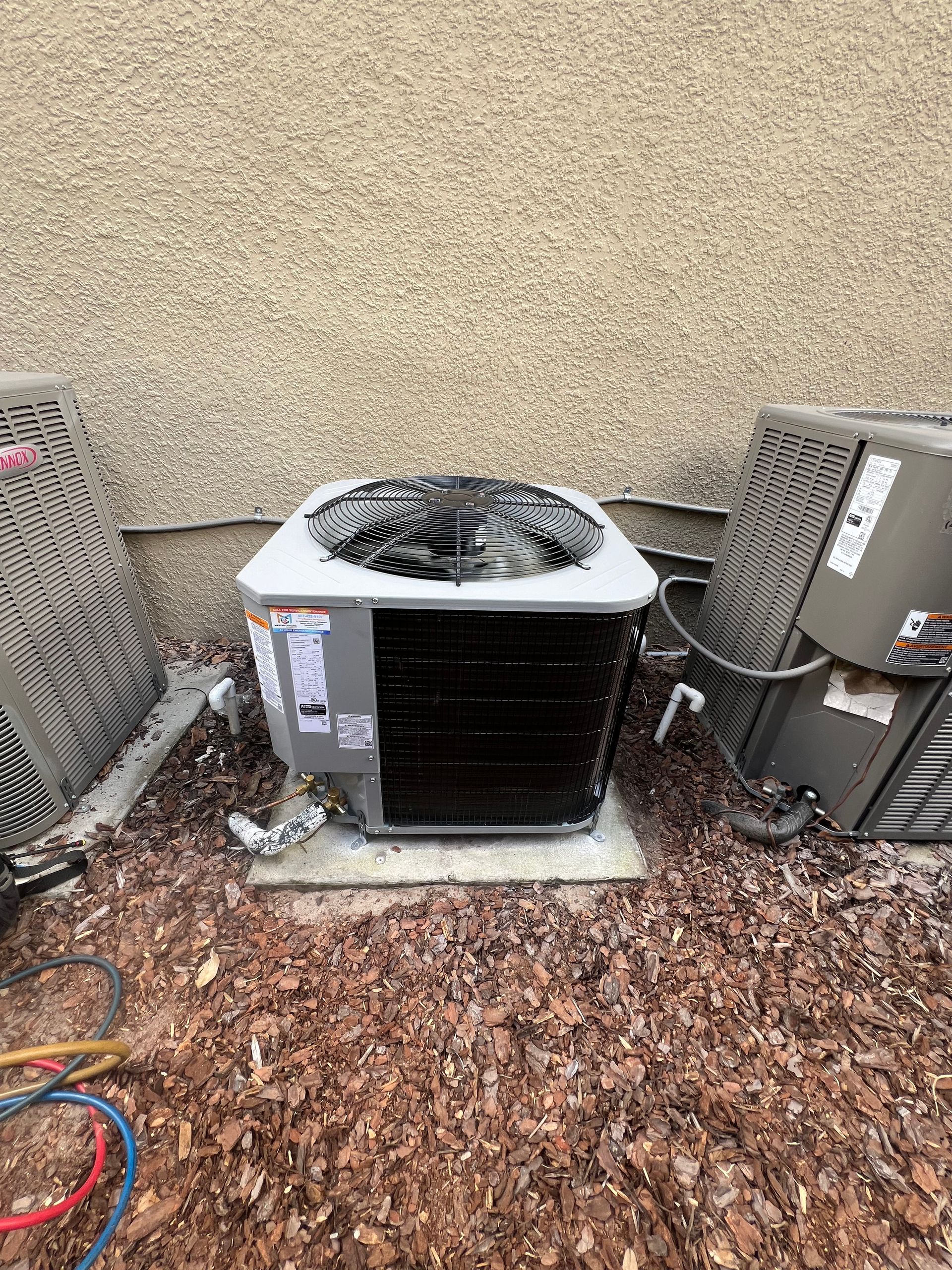 a couple of air conditioners sitting on top of a pile of mulch .