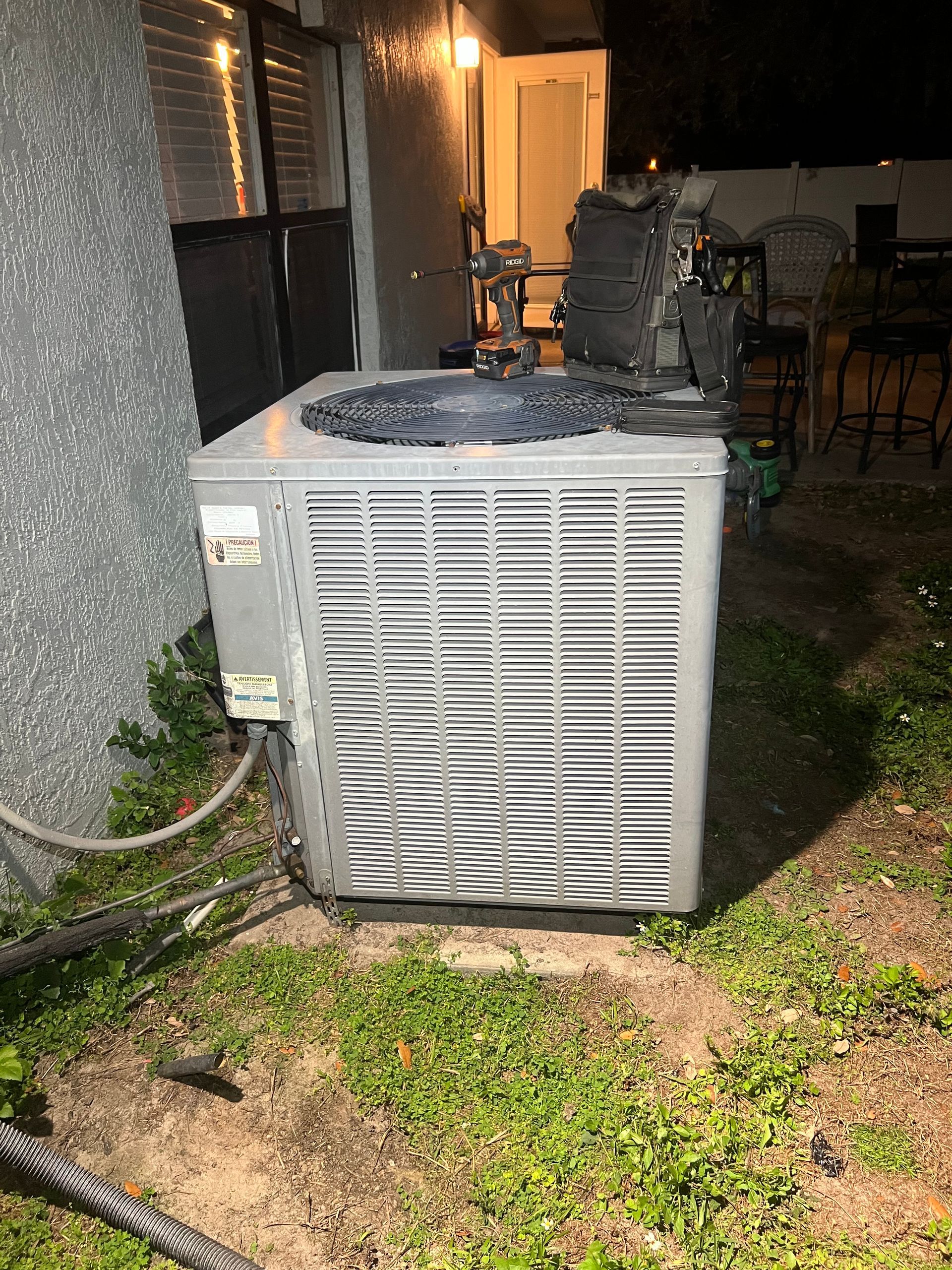 a large air conditioner is sitting in the grass outside of a house .