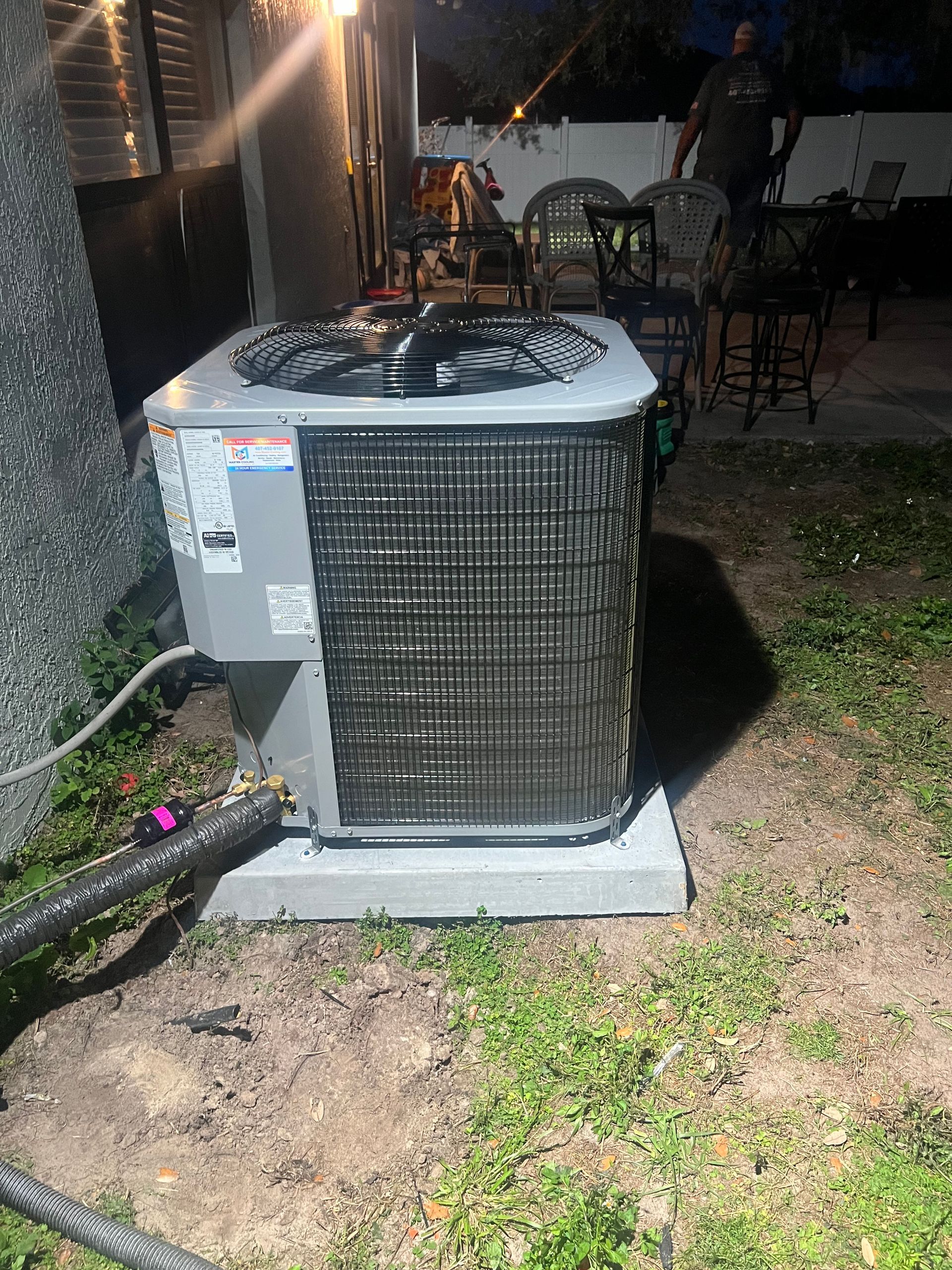 a large air conditioner is sitting in the grass in a backyard .