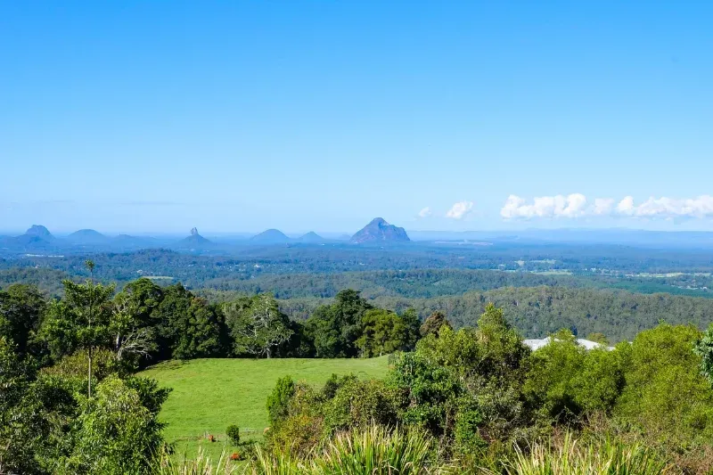 Panoramic view of green hills and the distinct volcanic peaks of the Glass House Mountains under a clear blue sky — Reynolds Built In Little Mountain, QLD