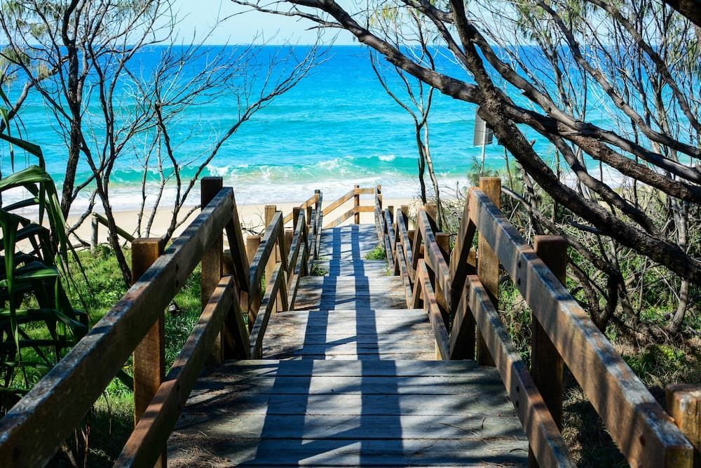Wooden Boardwalk Leading to a Sandy Beach With Turquoise Water — Reynolds Built In Mooloolaba, QLD
