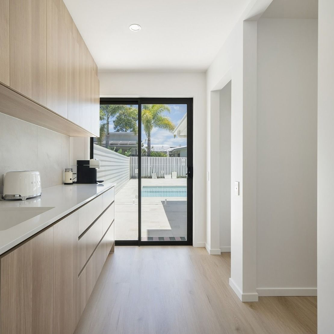 A Minimalist Kitchen With Light Wood Cabinets and White Countertops — Reynolds Built In Little Mountain, QLD