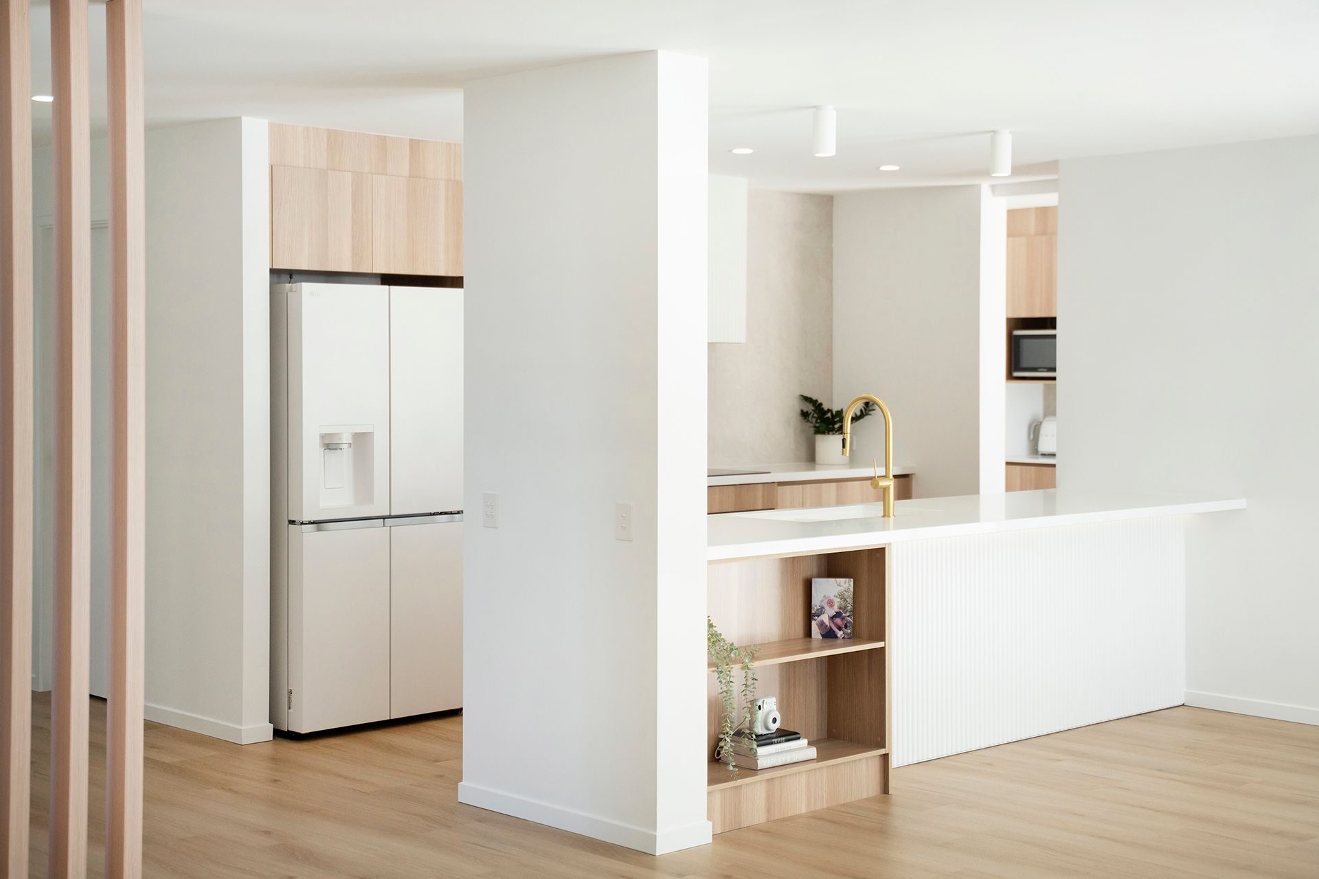 Bright Modern Kitchen With White Walls, Wood Floors, and a White Refrigerator — Reynolds Built In Alexandra Headlands, QLD