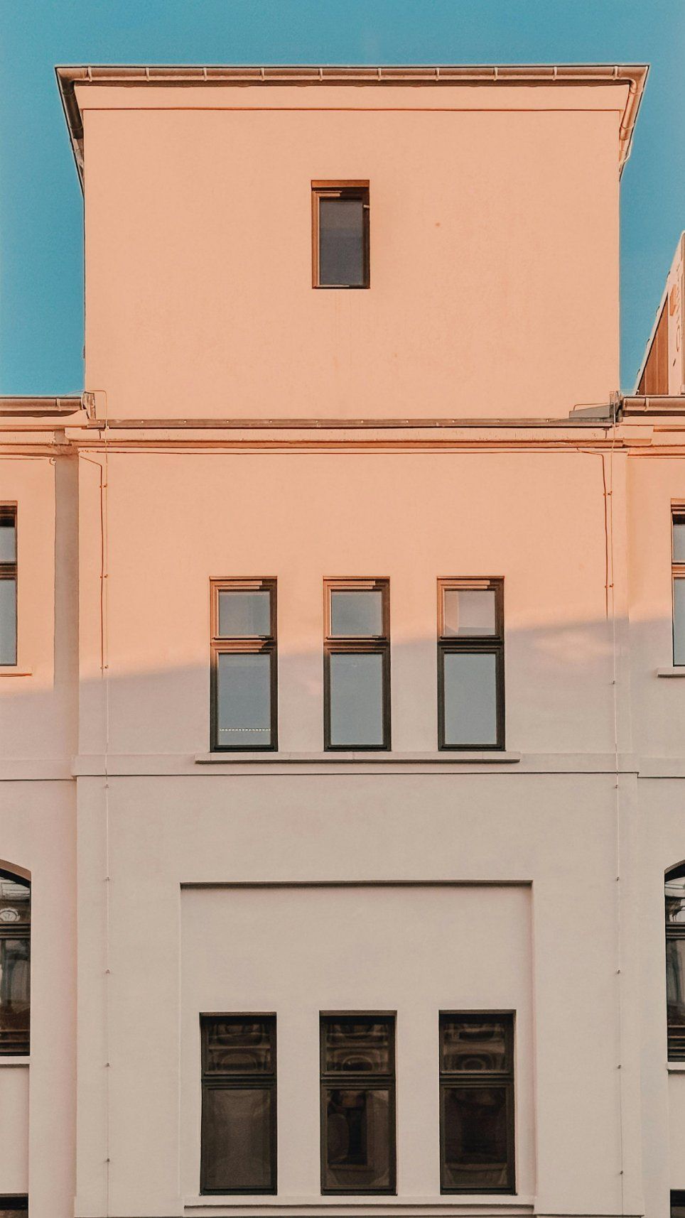 Pastel Pink and White Building Facade With Tall Windows Against a Blue Sky — Reynolds Built In Moffat Beach, QLD