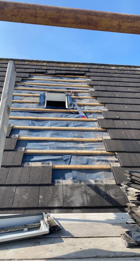 Roof with missing tiles, revealing underlayment and rafters, with a small vent.