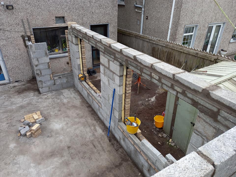 Construction of a building's exterior walls using gray concrete blocks.