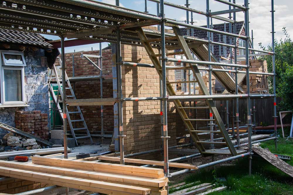 Scaffolding surrounds a building's brick wall during renovation