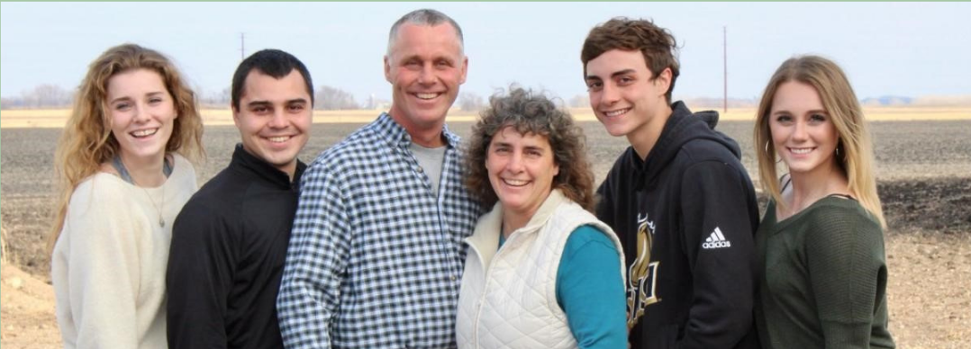 A family is posing for a picture in a field.