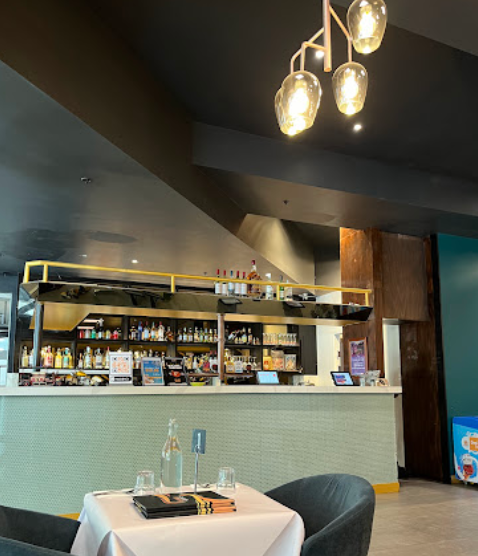 A restaurant with a table and chairs in front of a counter