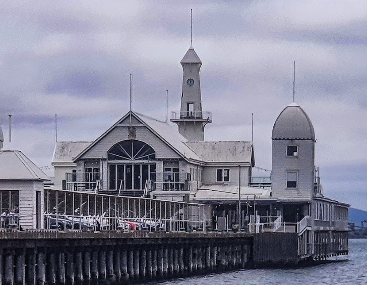 A large white building with a dome on top sits next to a body of water