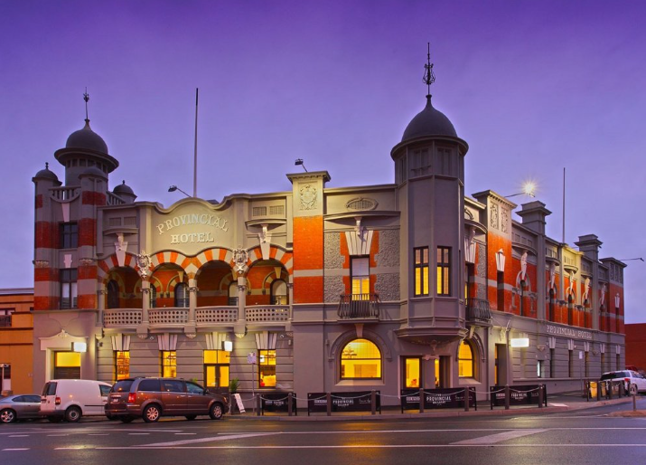A large building with cars parked in front of it at night.