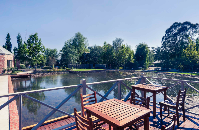 A wooden deck with tables and chairs overlooking a lake