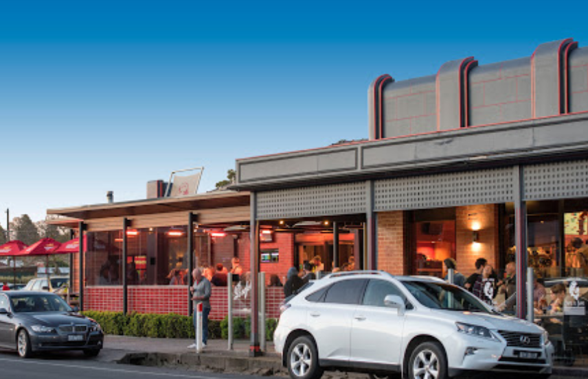 A white lexus is parked in front of a restaurant.