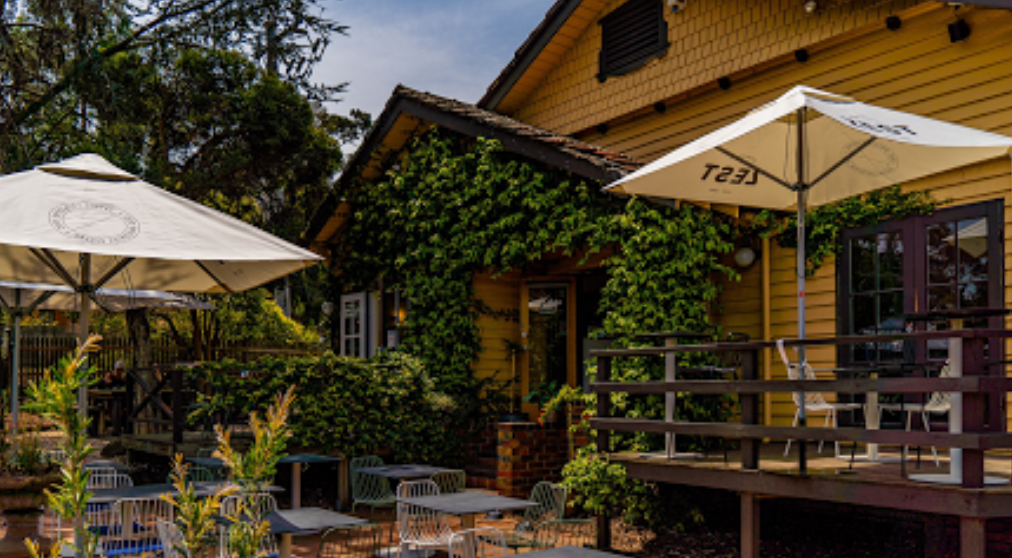 A yellow house with tables and umbrellas in front of it.