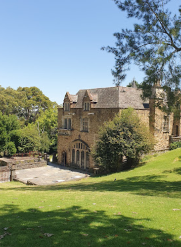 A large stone house sits on top of a grassy hill
