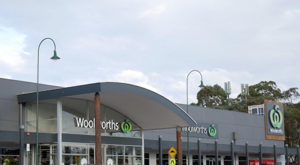 The front of a woolworths store with a cloudy sky in the background.