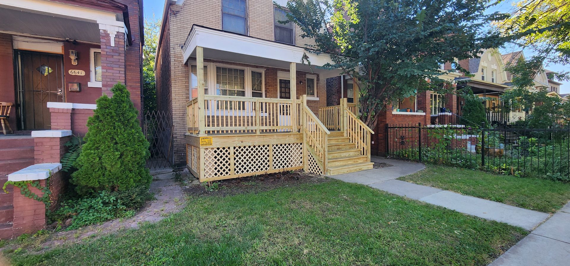 A brick house with a wooden porch and stairs in front of it.