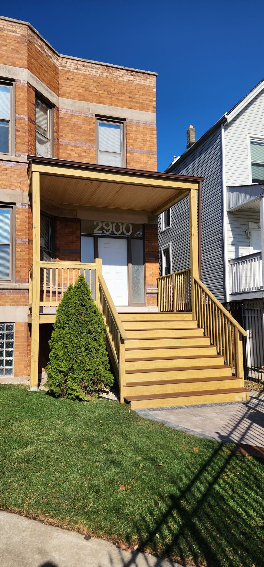 A brick house with a wooden deck and stairs in front of it.