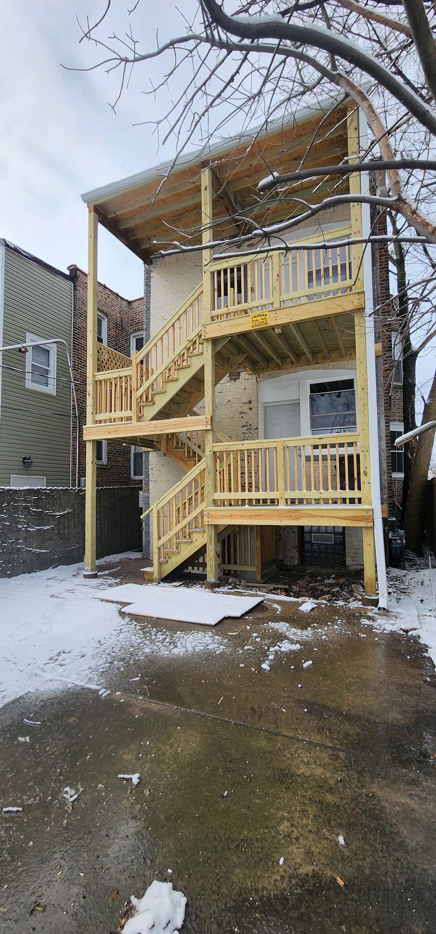 A house with a wooden deck and stairs in the backyard.