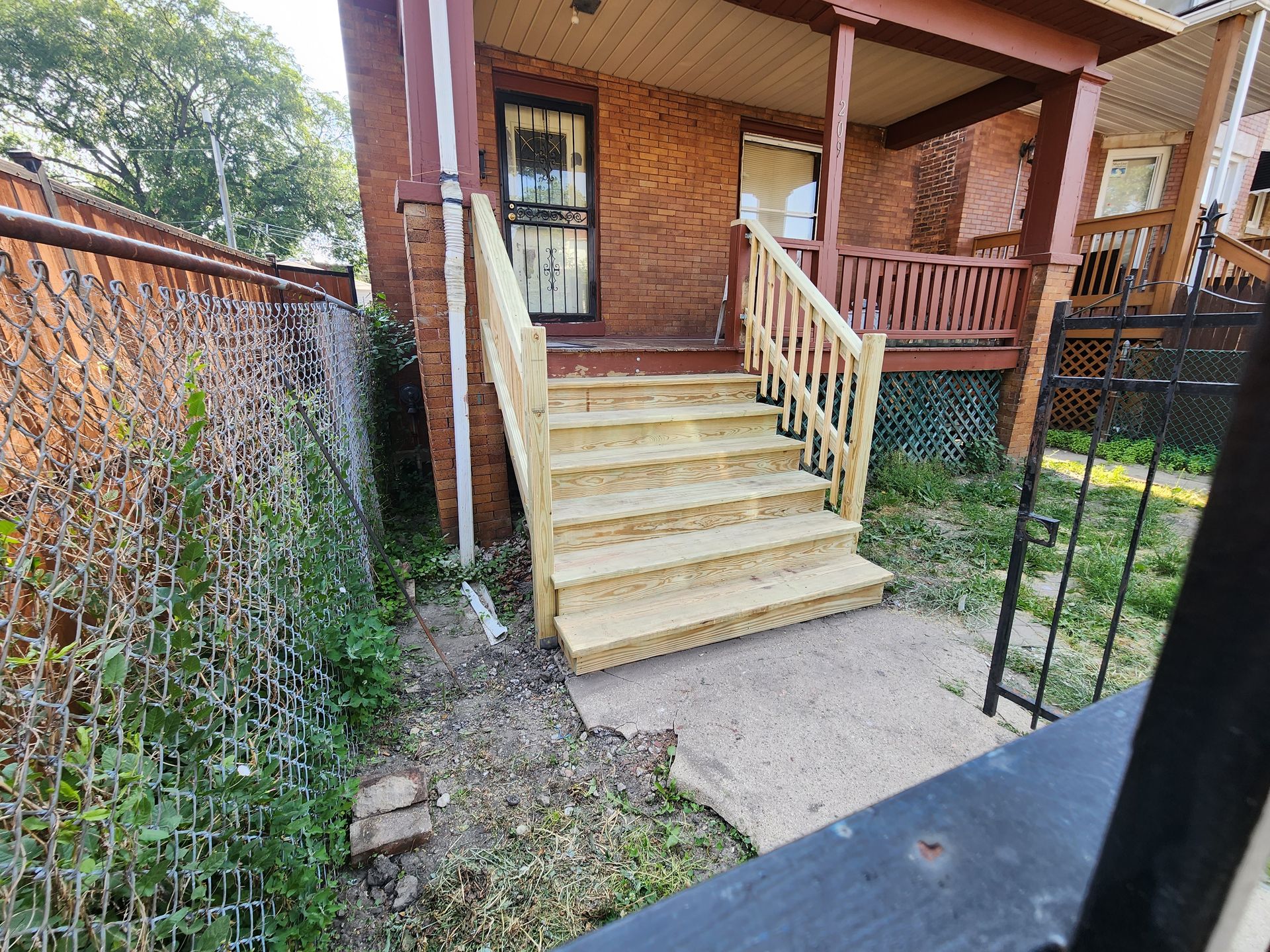 A brick house with a wooden porch and stairs.
